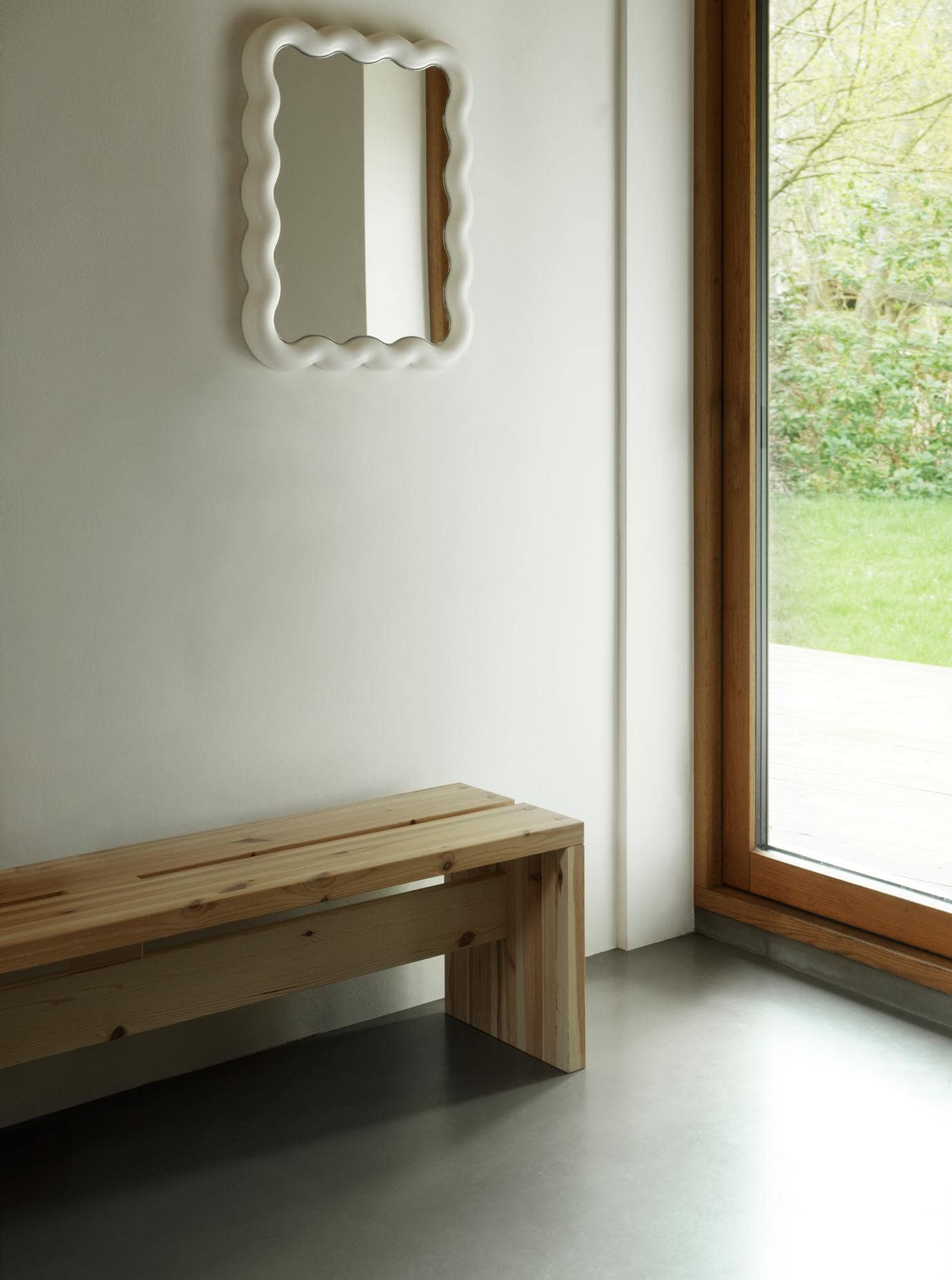 Træbænk og bølgede spejl på væggen