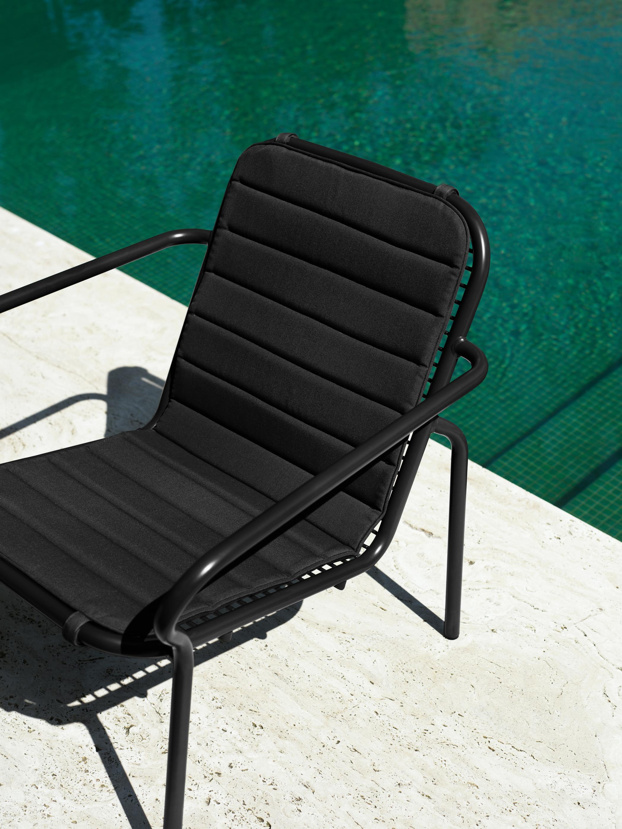 Sort lounge stol med hynde i, ved en pool