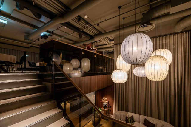 Hotel område med trappe og store loftlamper i grå og beige