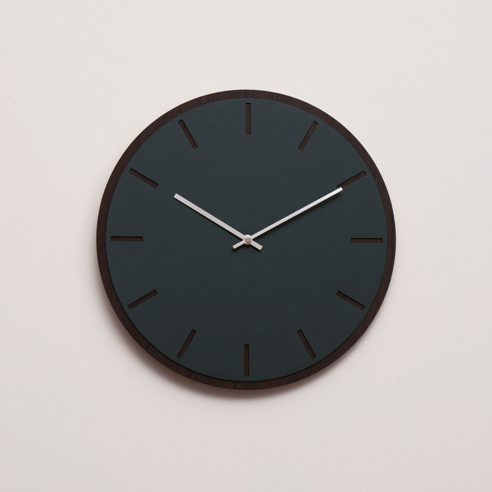 Ur i farven conifer, med mørk træbaggrund og sølv viser