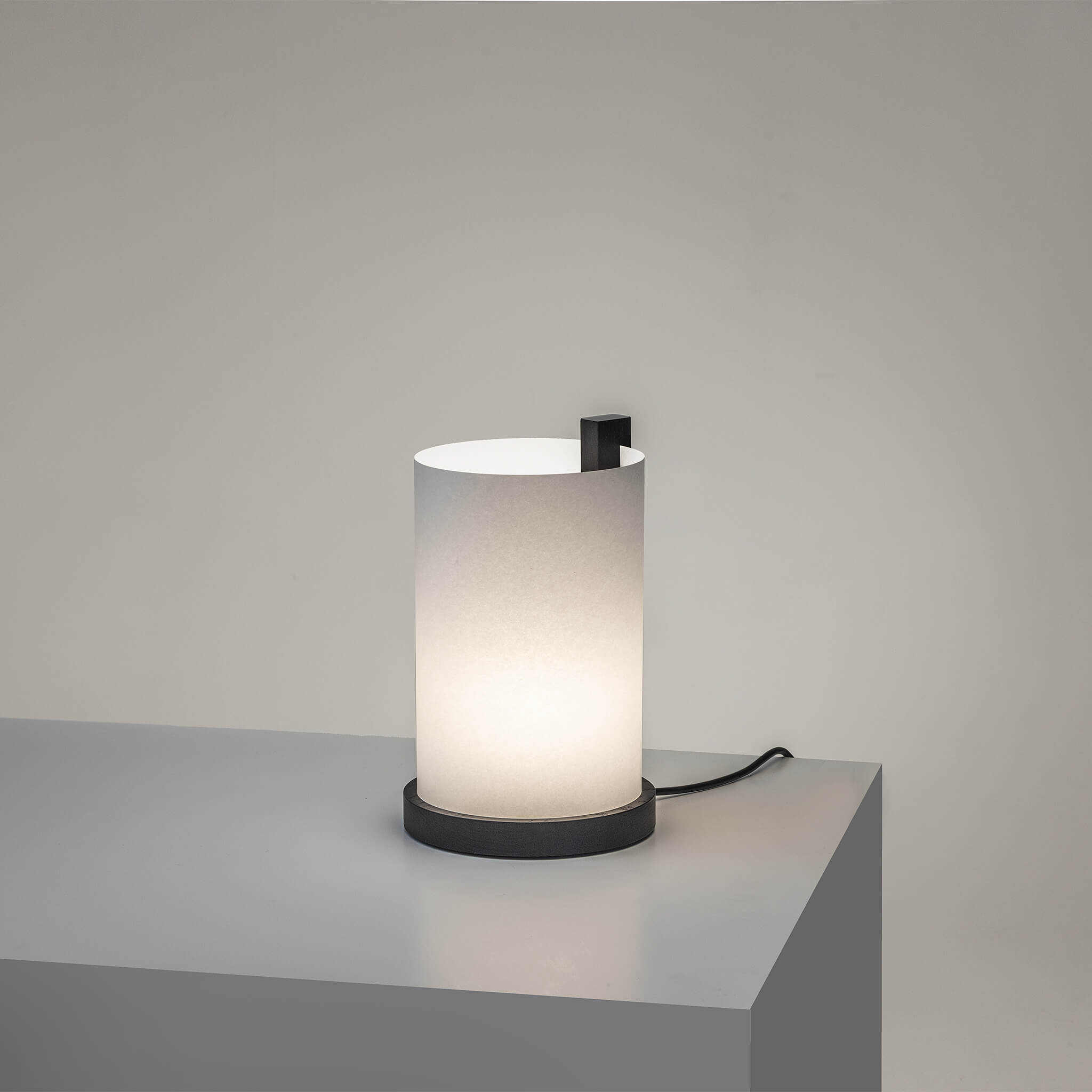 Lille bordlampe med lys tændt og en sort træramme.