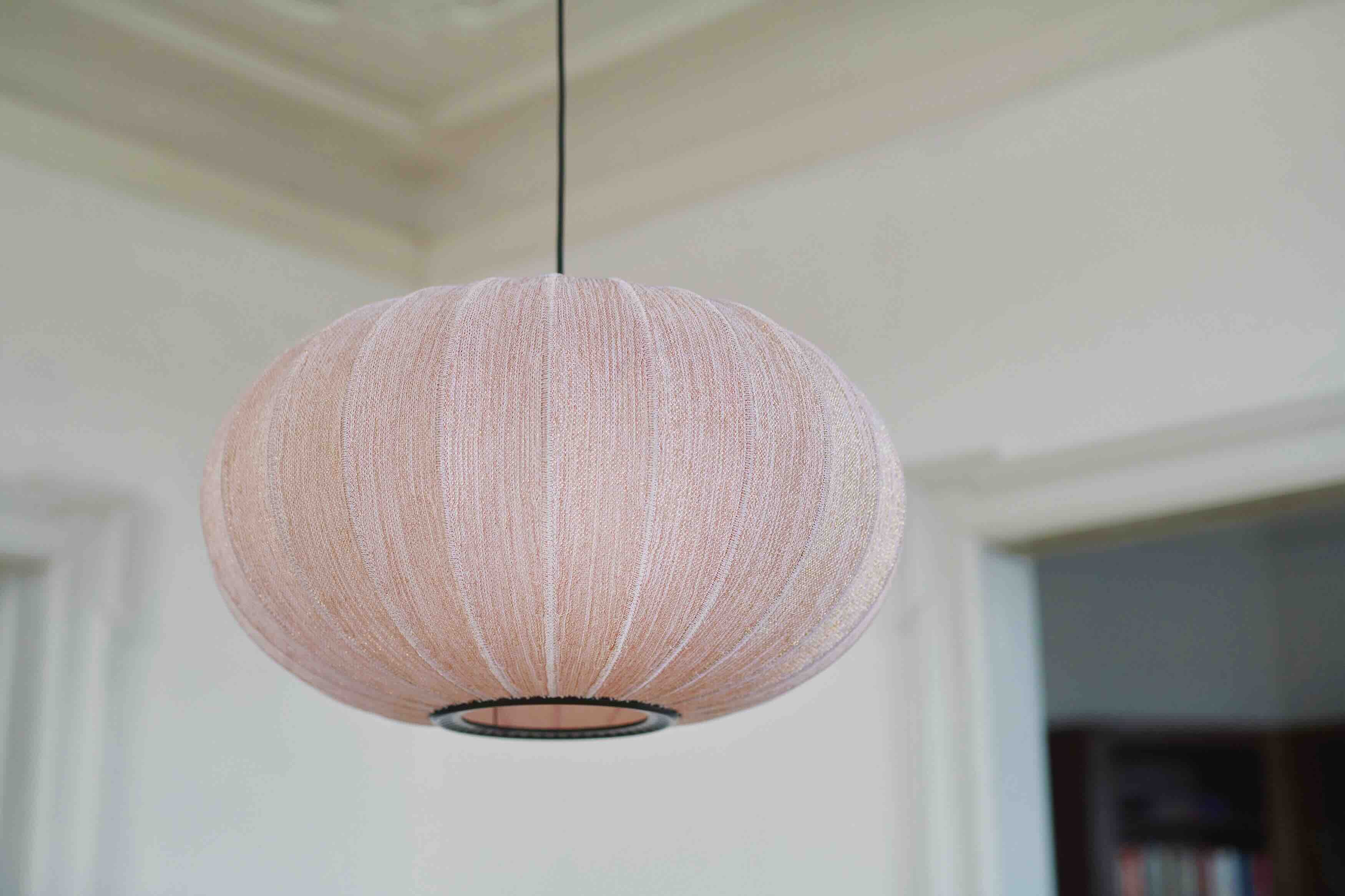 Oval lampe i lyserød med sorte syninger og ledning