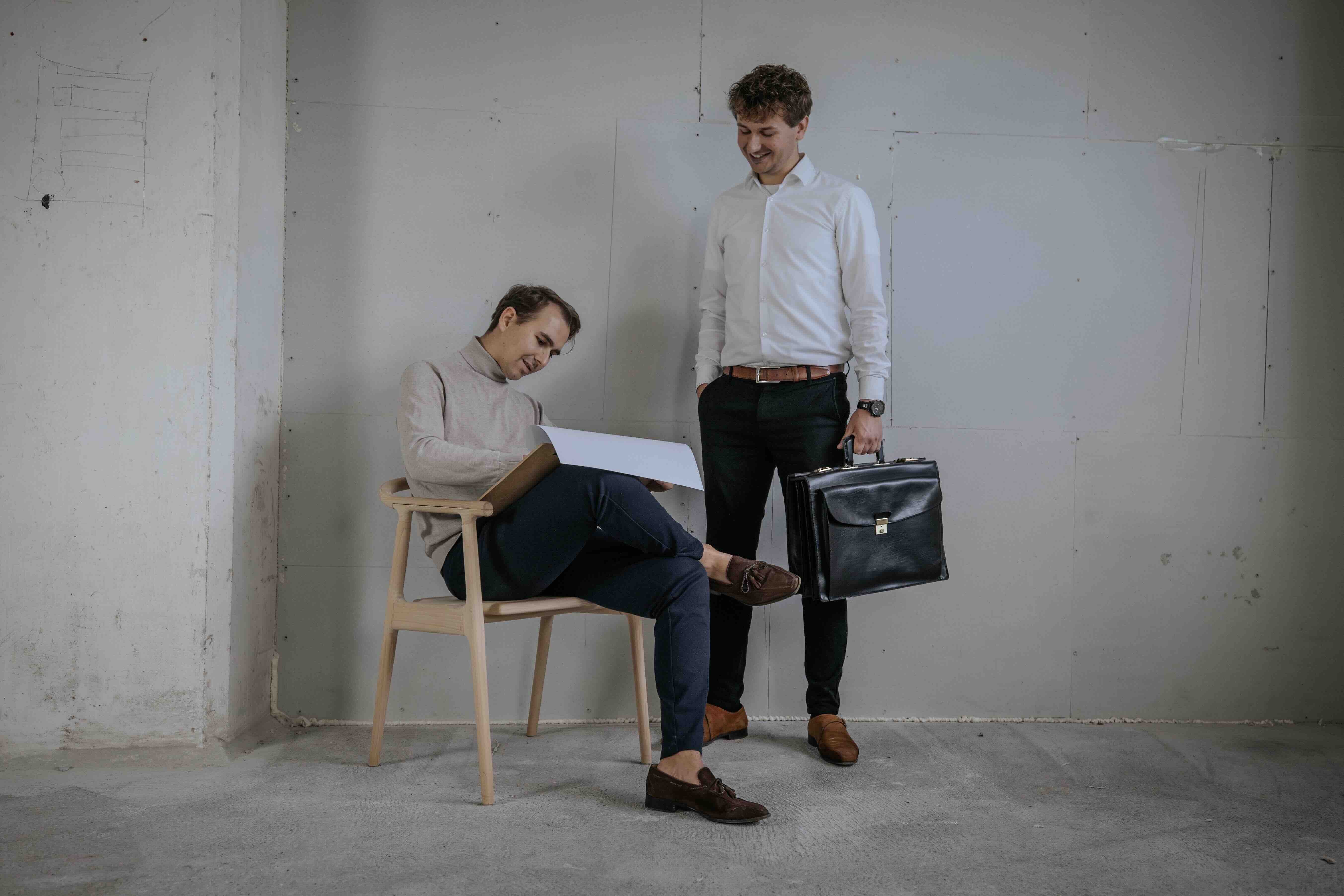 To drenge hvor den ene tegner og den anden står med en mappe