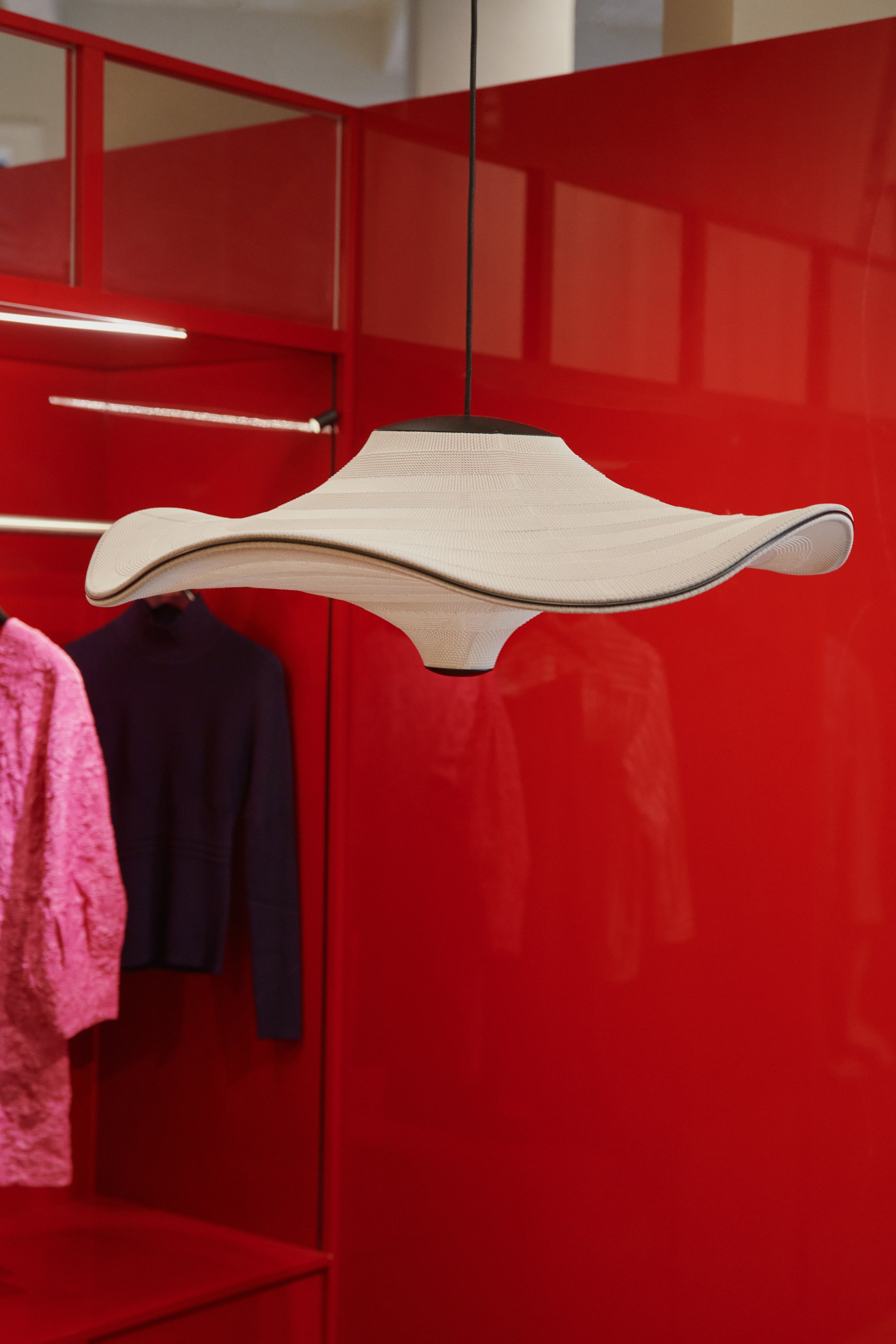 Loftlampe hænger bag et rødt garderobeskab