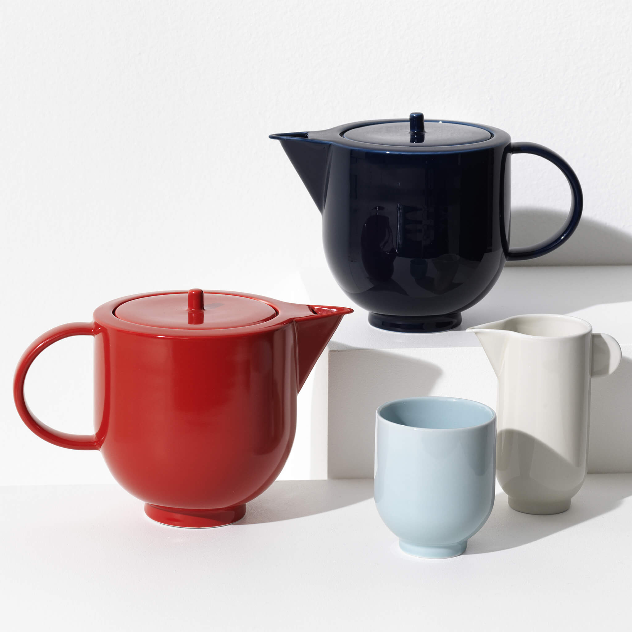 Nærbillede af porcelæn te-sæt med 2 tekander, en pitcher og et krus.