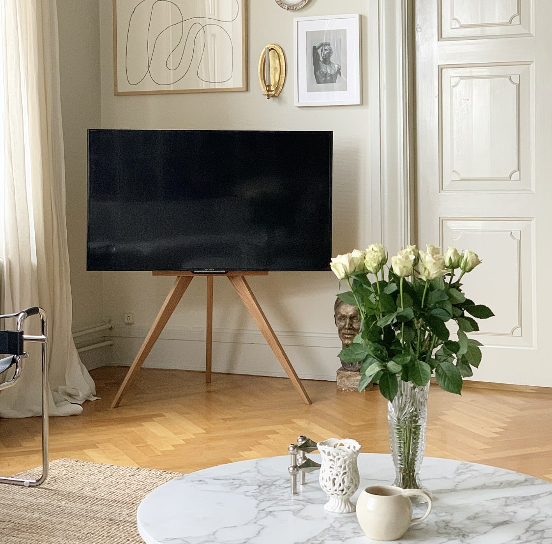 Tv stander i eg i en stue, står i hjørnet foran sofabord