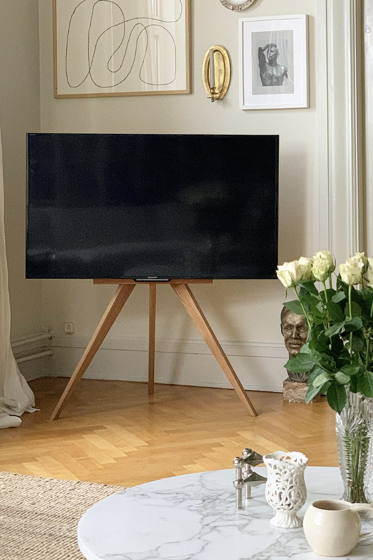 Tv stander i eg i en stue, står i hjørnet foran sofabord