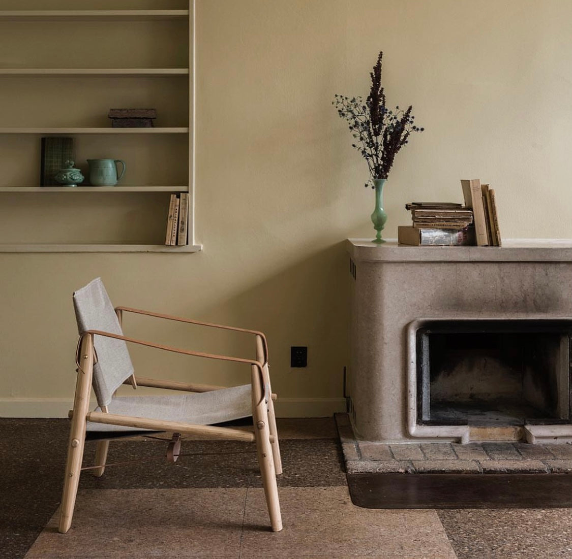 Loungestol i træ med beige stof ved en pejs