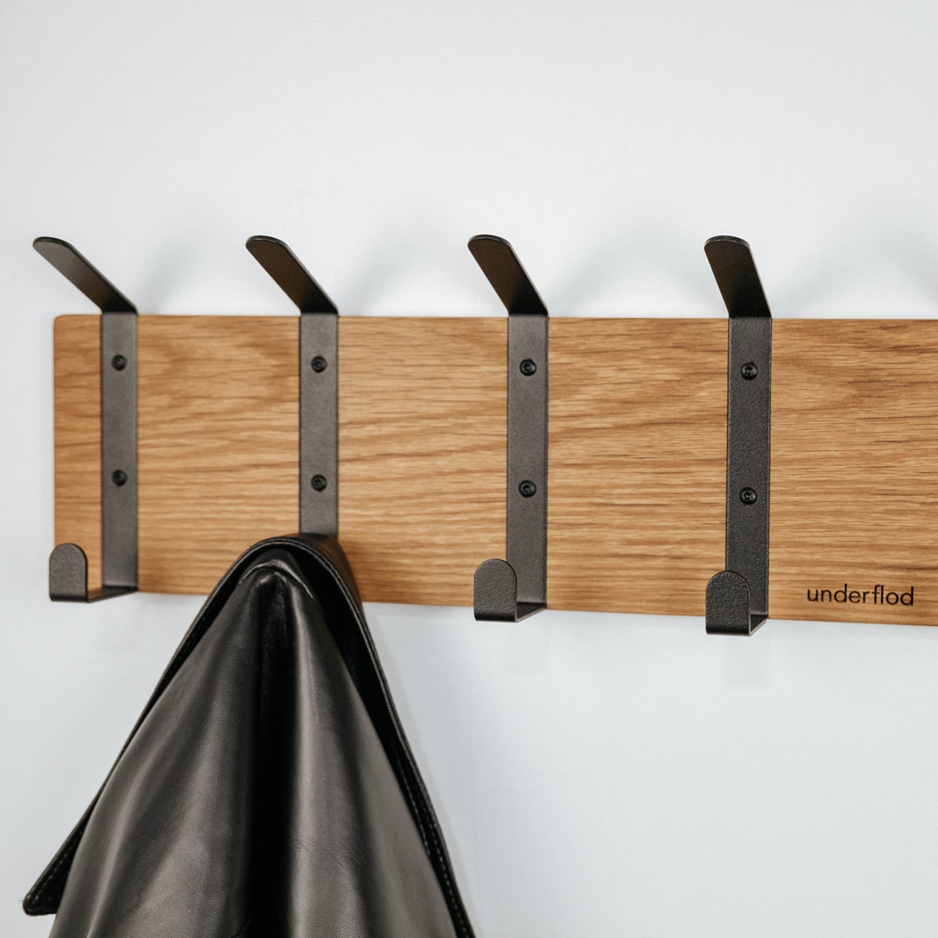 Billede af knagerække med 4 knager, med én jakke på