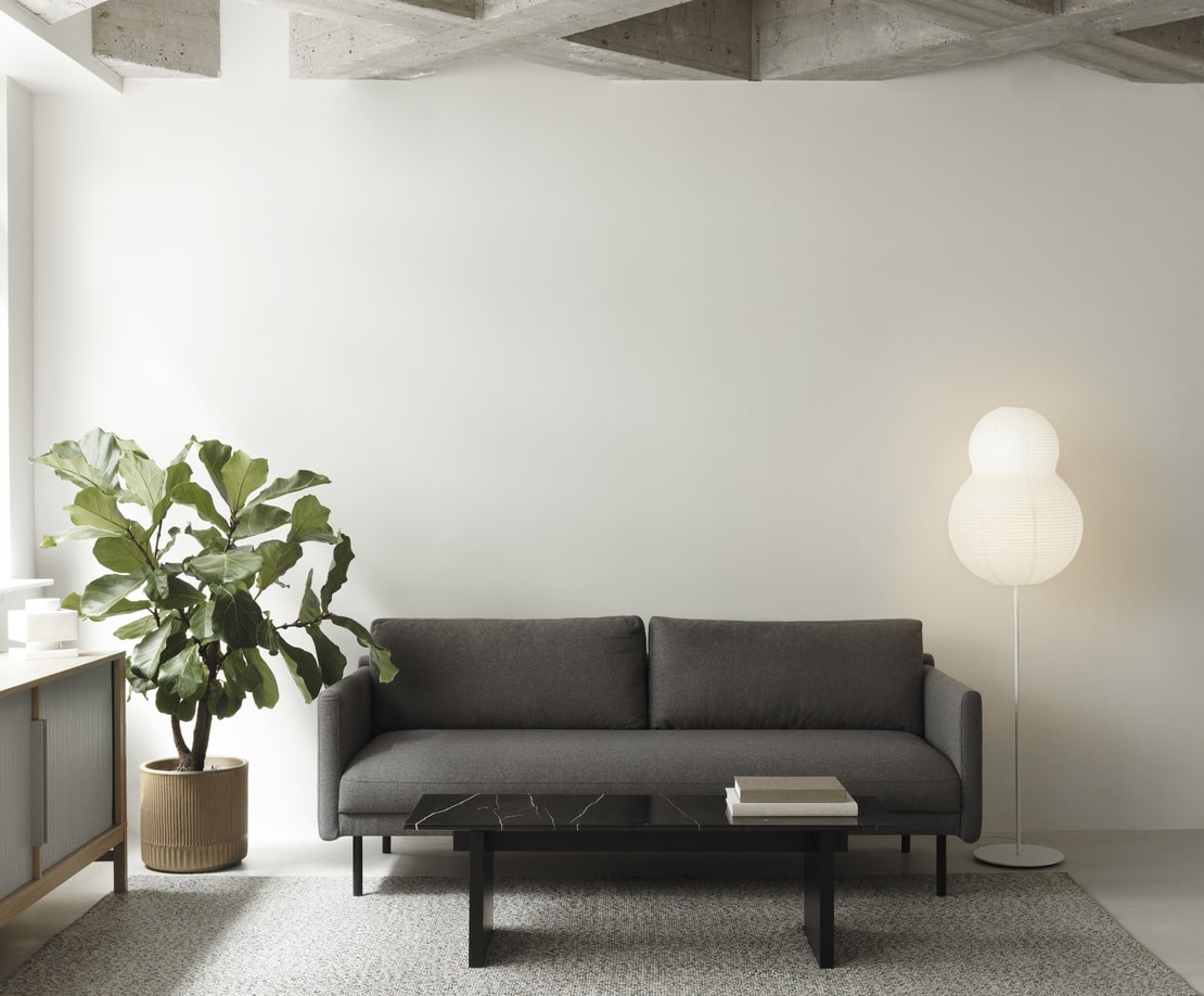 2 personers mørkegrå sofa i stuen med sofabord og plante