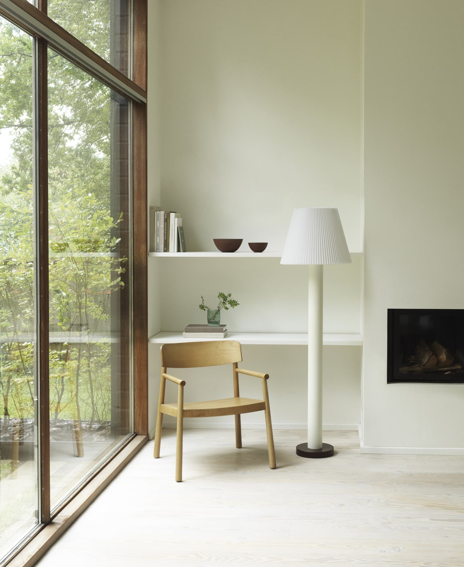 Loungestol i træ der står i hjørne med hvid lampe