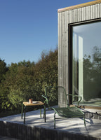 Grøn liggestol på terrasse med lille træ bord med grønne ben