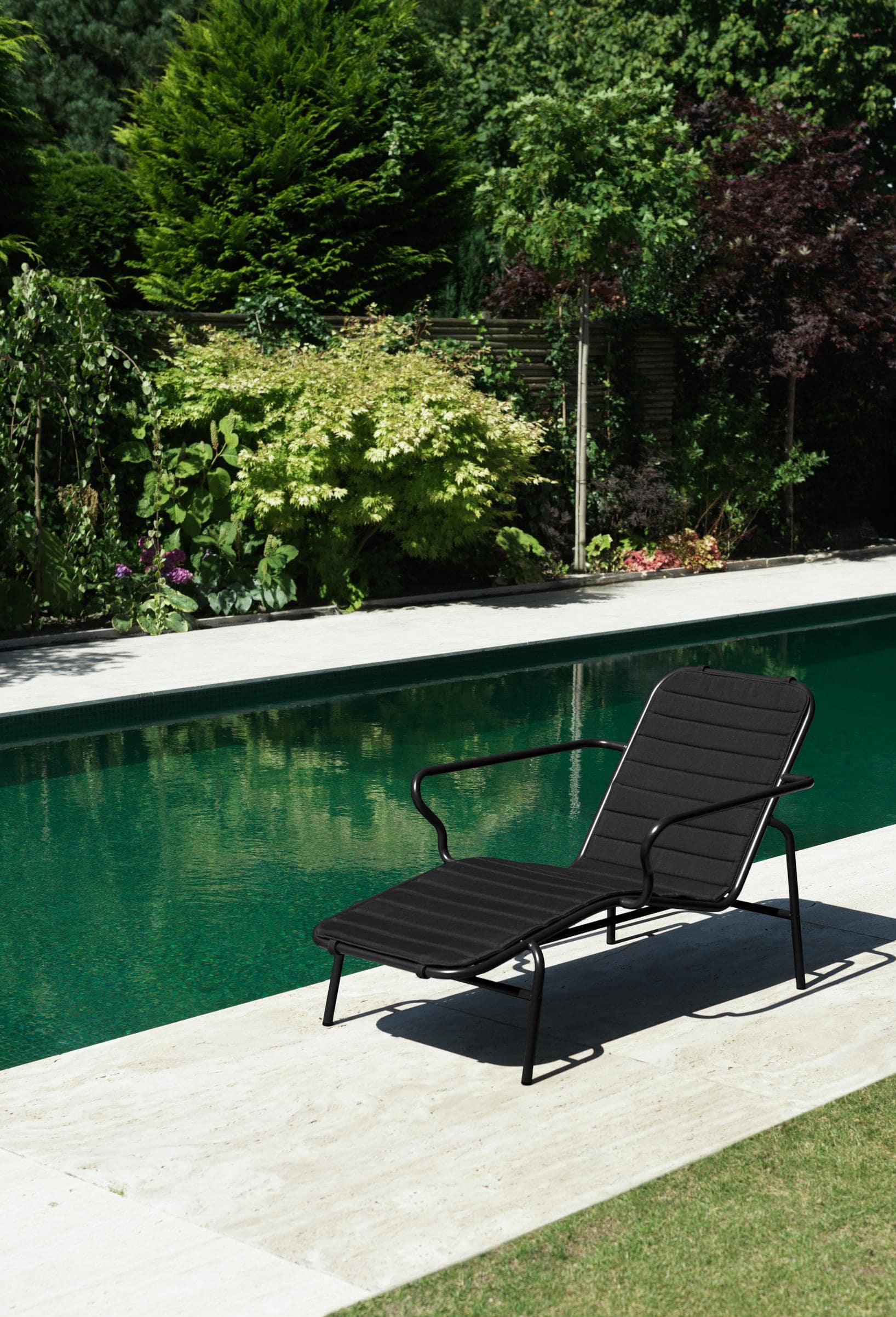 Sort liggestol med hynde i, ved en flot pool