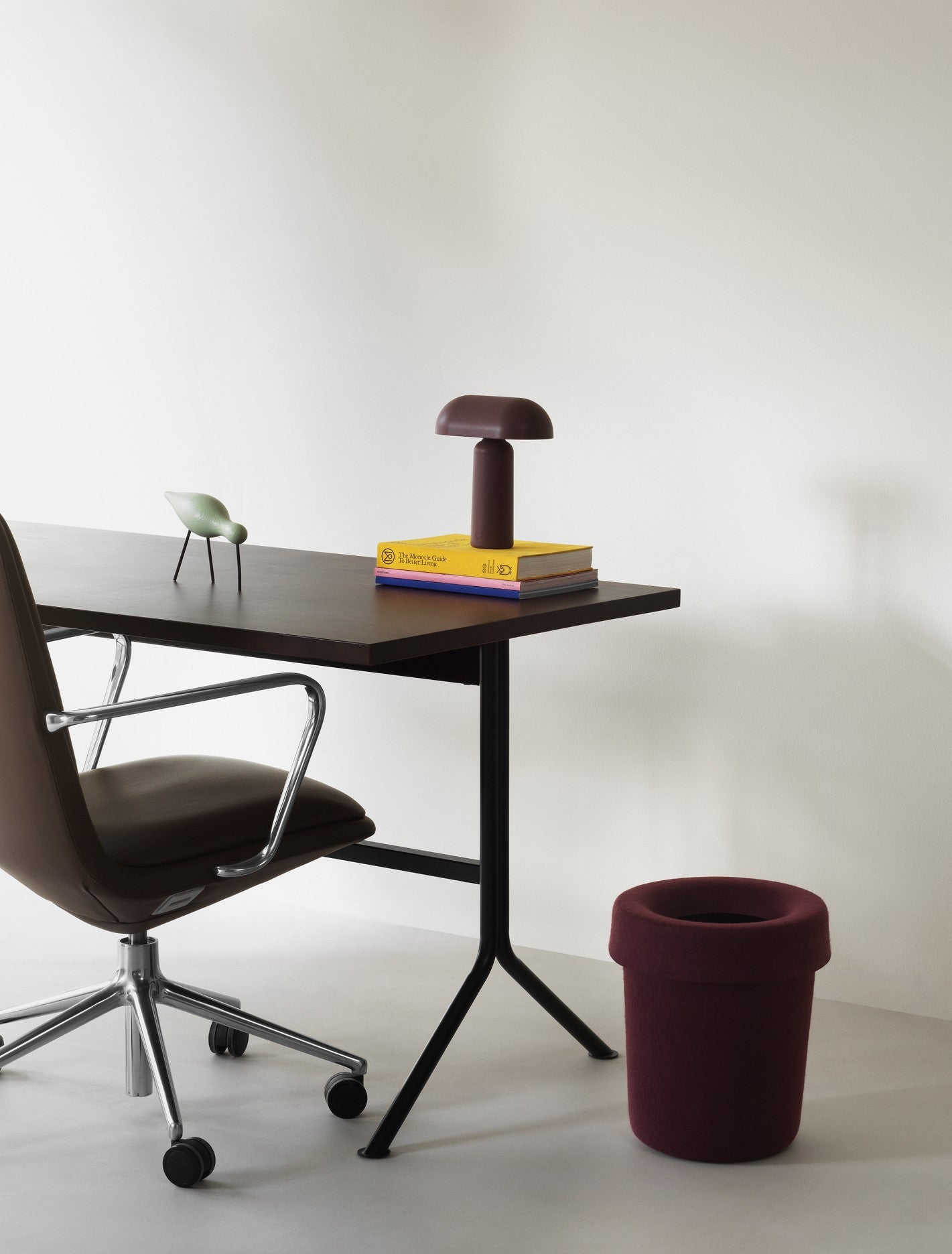 Skrivebord med kontorstol og skraldespand i vinrød