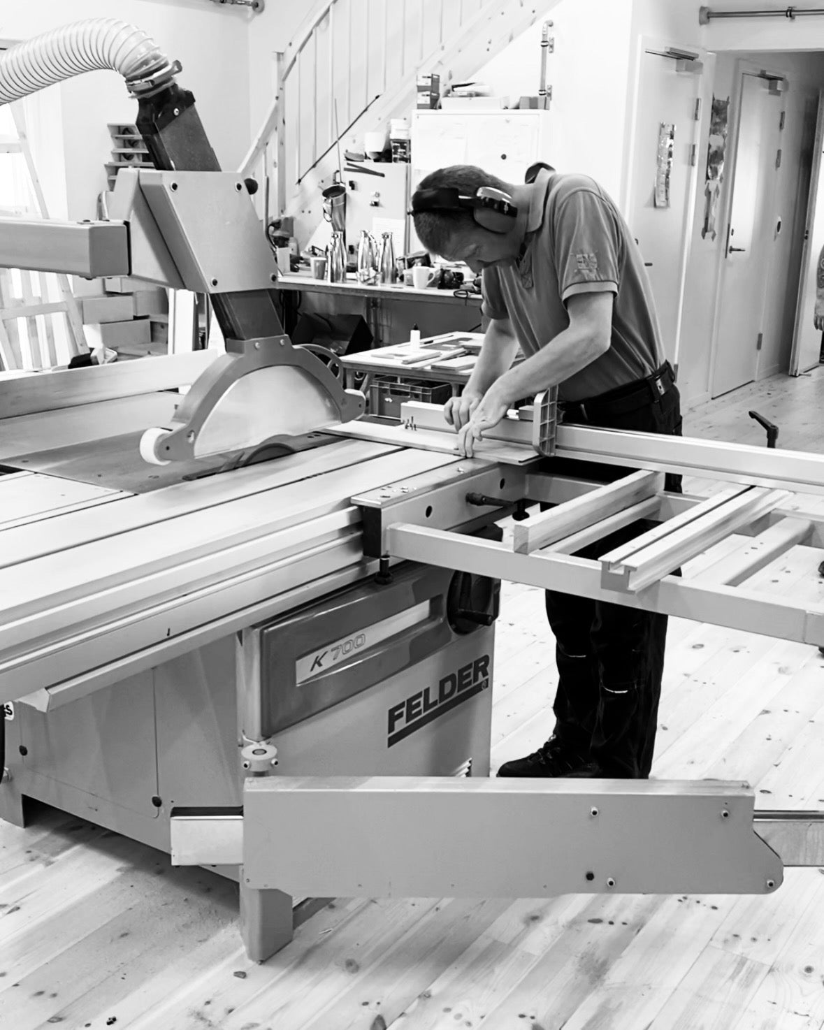 Håndværker i værksted med hørebøffer der arbejder med rundsav