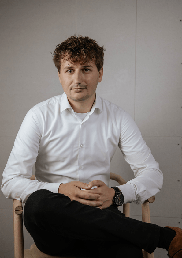 Billede af mads der sidder på en stol og smiler med lukket mund