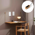 Kontorplads med væghængt skrivebord og en træstol. Et billede af en stikdåse af træ. 