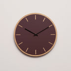 Ur i burgundy med lys træramme og sort viser 