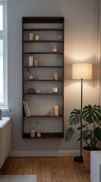 Vægreol af træ med 8 rum. På hylderne er der pynteting, og ved siden af står der en lampe og en plante. 