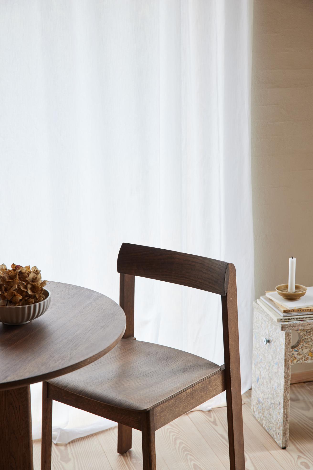 Rundt sofabord og spisebordsstol i mørk træ