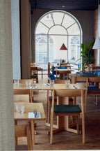 Restaurant med egetræsmøbler og polstret sæde i grøn og blå