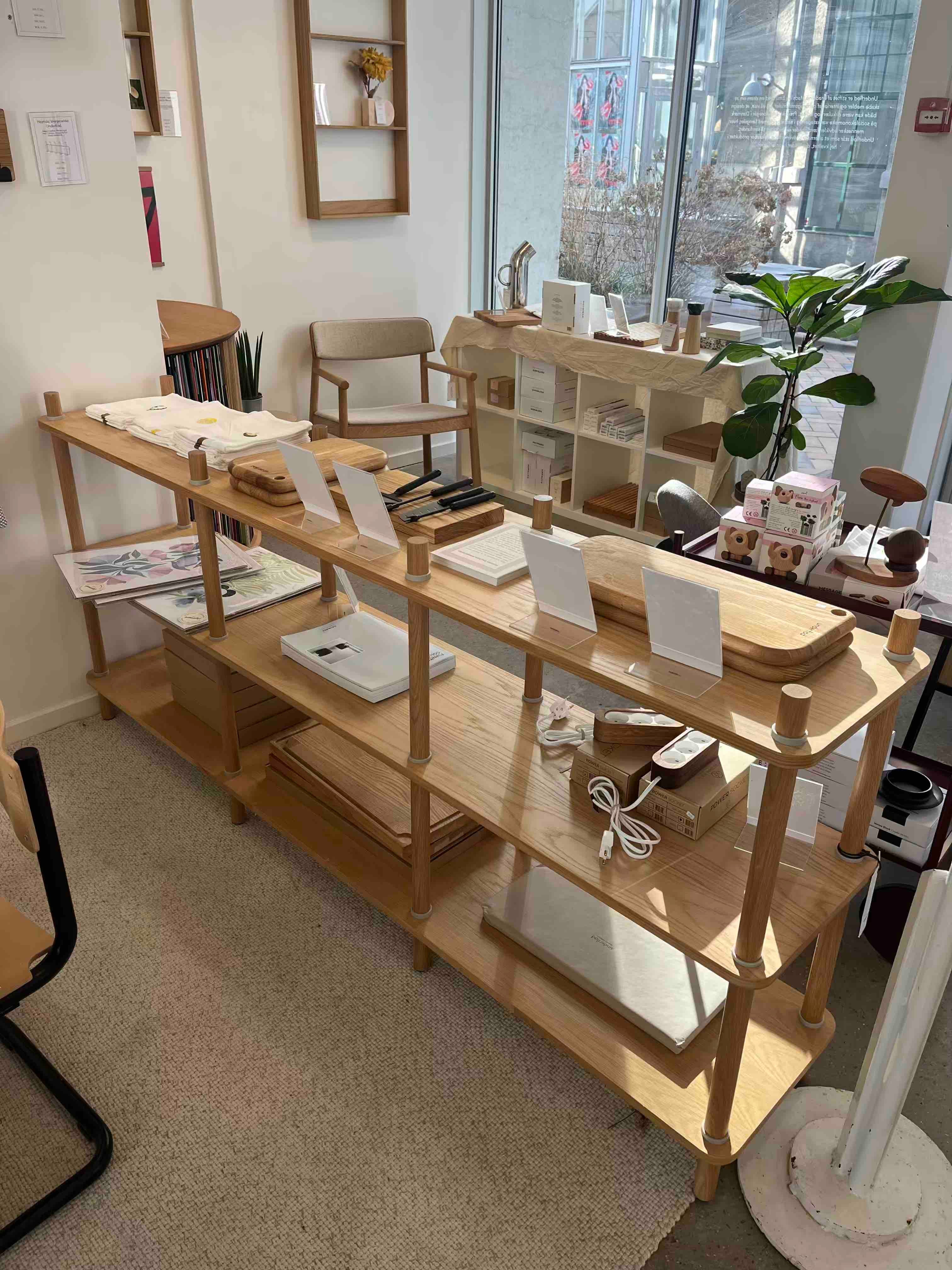 Reol i træ med skærebrætter, køkkenredskaber og viskestykker i butik