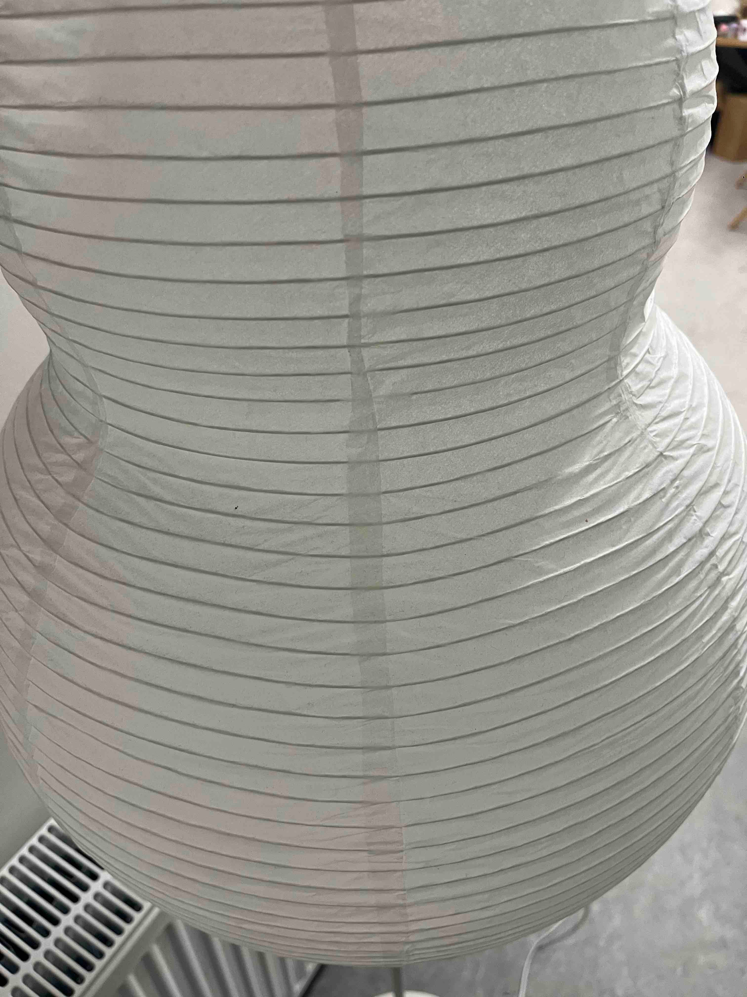 Nærbillede af hvid gulvlampe med lampeskærm formet som en jordnød