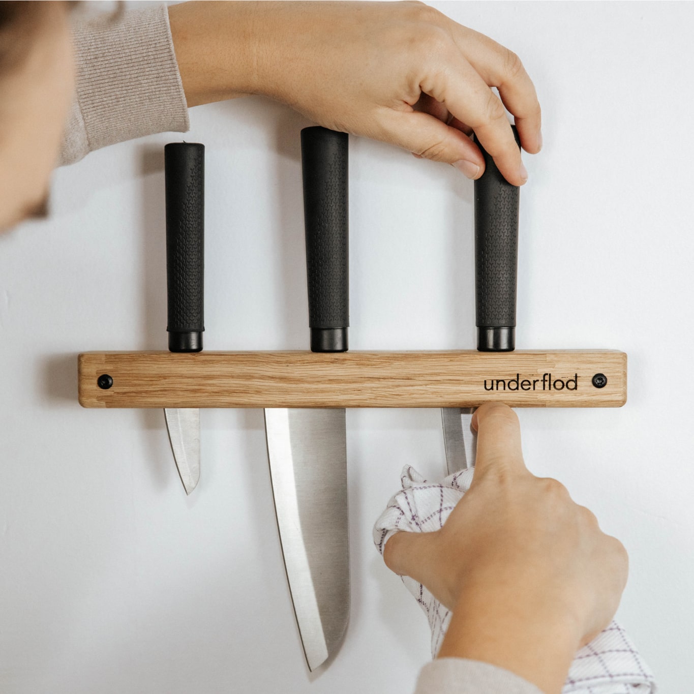 Billede af lille knivholder med 3 knive i, hvor én mand retter på knivene