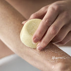 En hånd påfører en sæbebar direkte på armen.