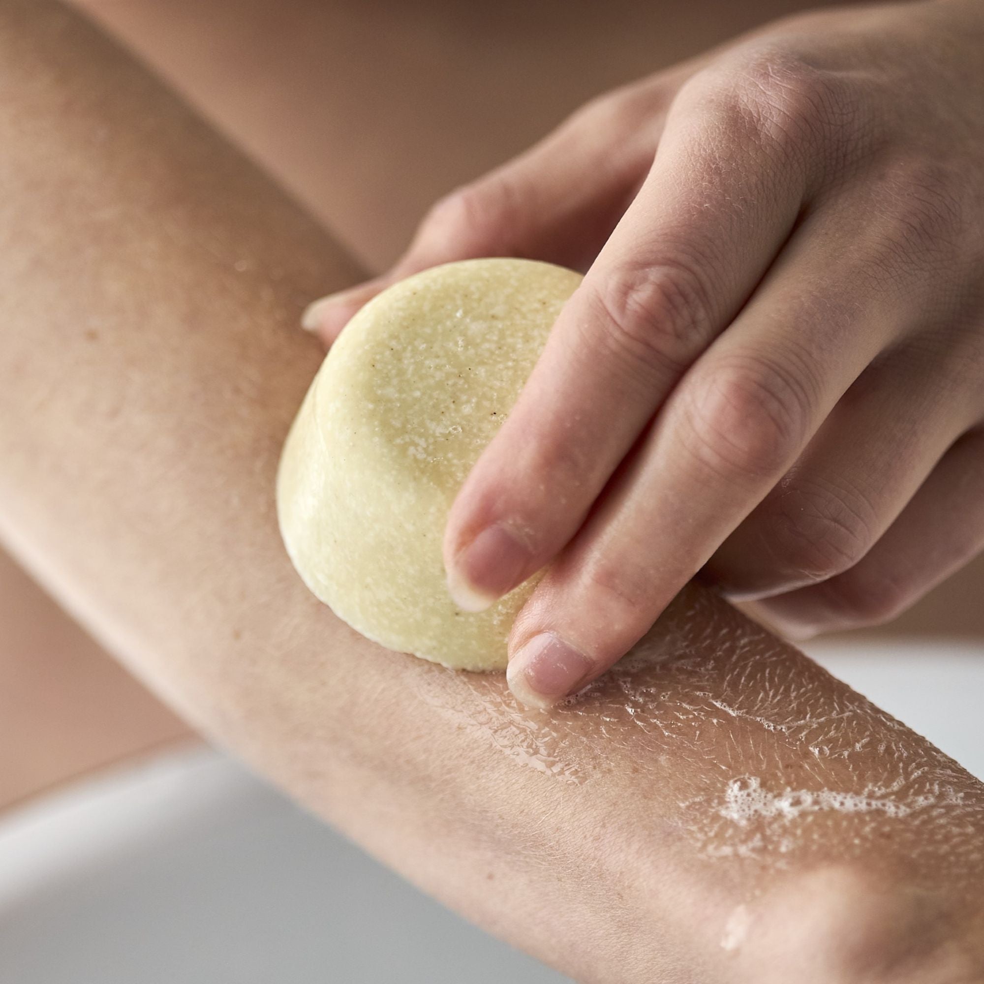 En hånd påfører en sæbebar direkte på armen.