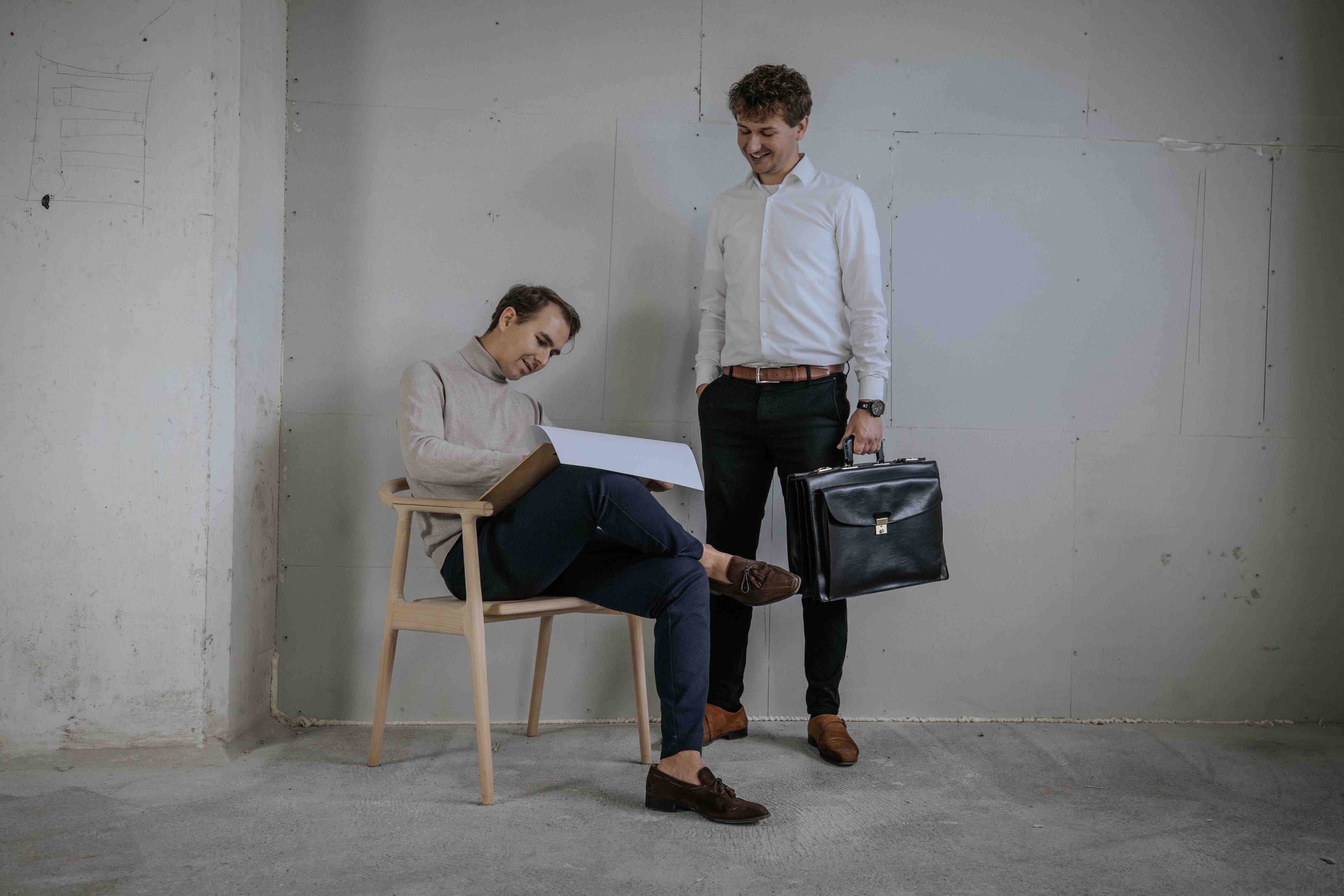 To drenge hvor den ene tegner og den anden står med en mappe