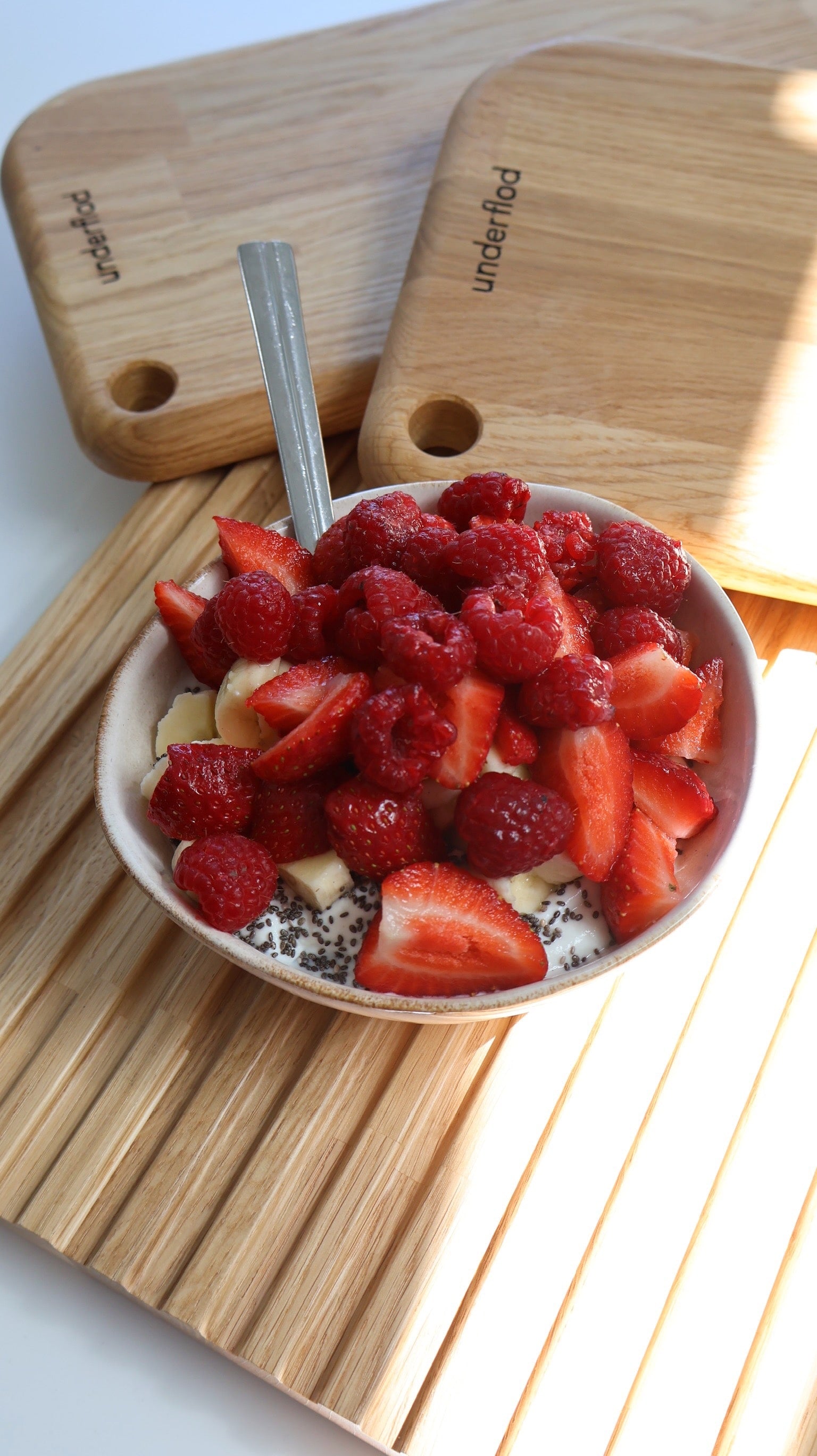 Skål med morgenmad og bær på skærebræt