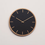 Sort ur med lys træramme og kobber viser 