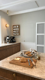 Træskærebræt på køkkenø klargjort til morgenmad med friske boller og marmelade