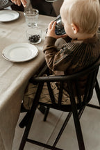 Dreng sidder i højstol i mørk bejset egetræ