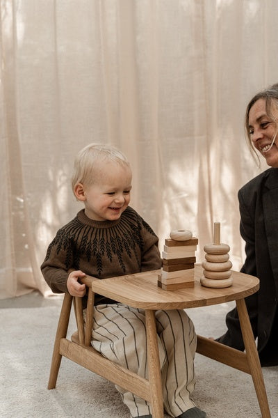 Barn leger i sin børnestol i egetræ