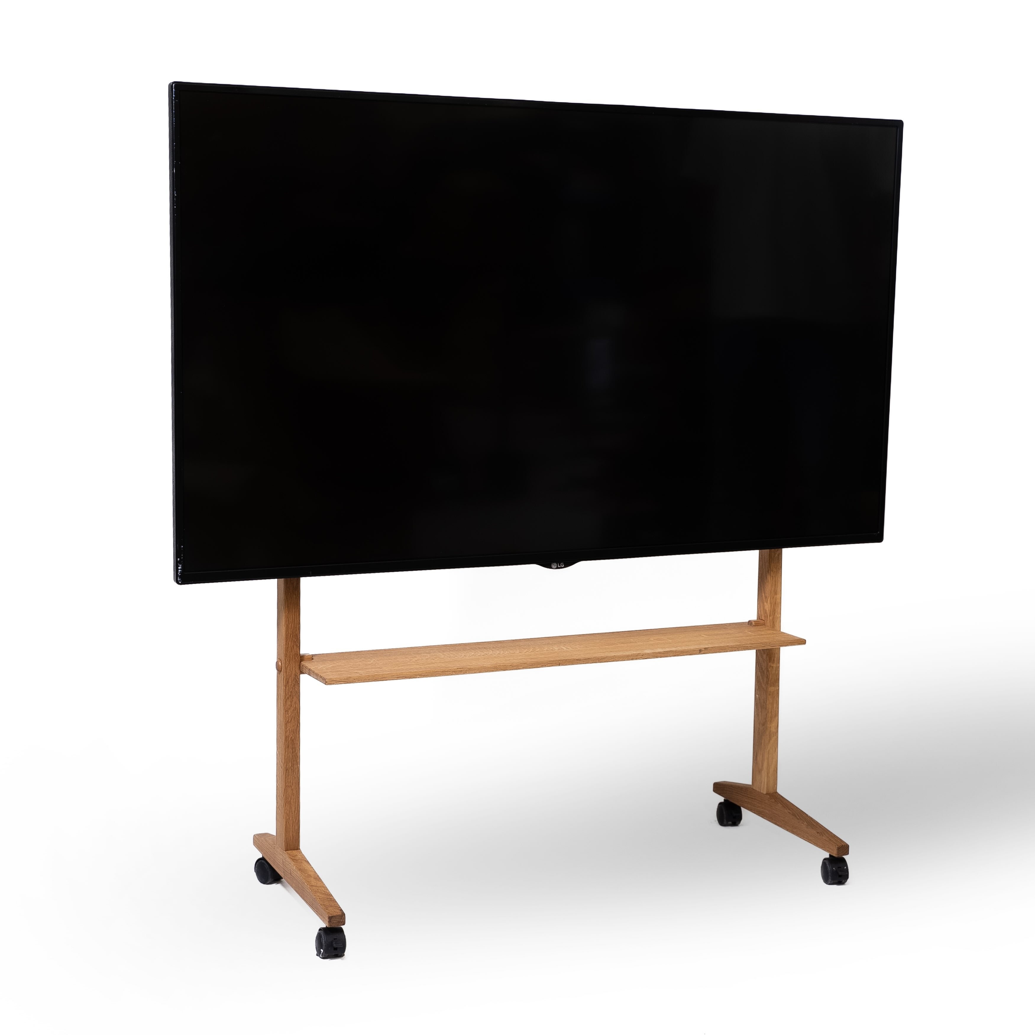 Tv på tv-stander af træ på hjul, med en træhylde. Hvid baggrund. 