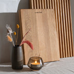 Billede af tørret blomster i vase, et starinlys og 2 stående skærebrætter i egetræ