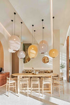 Spisestue med bord og stole i træ, med store loftlamper i pastel farver