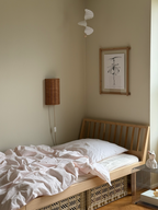 Et soveværelse med en trærramme og et sort/hvidt kunsttryk over sengen. 