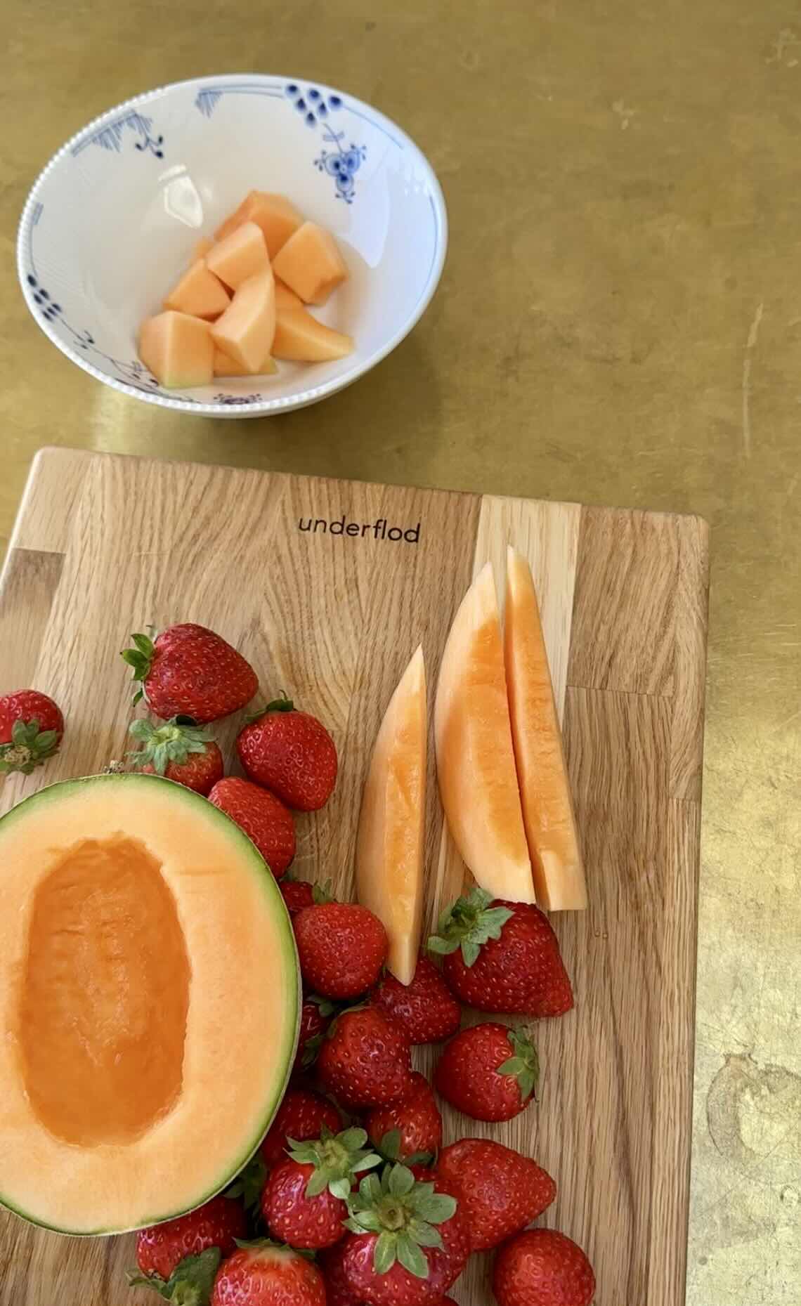Melon og jordbær skæres på skærebræt