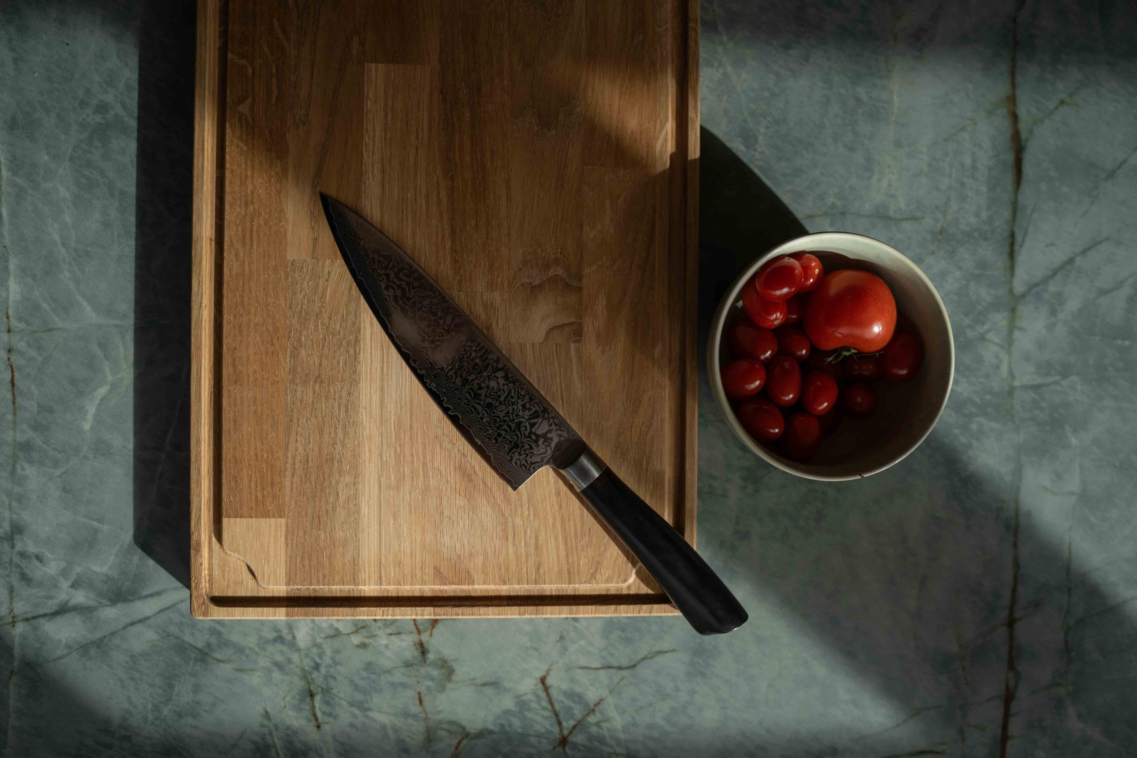 Skærebræt med saftrille, med en kniv og en skål med tomater