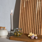 Billede med stående skærebræt og lille tapasbræt med tapasanretning på og ét levende lys